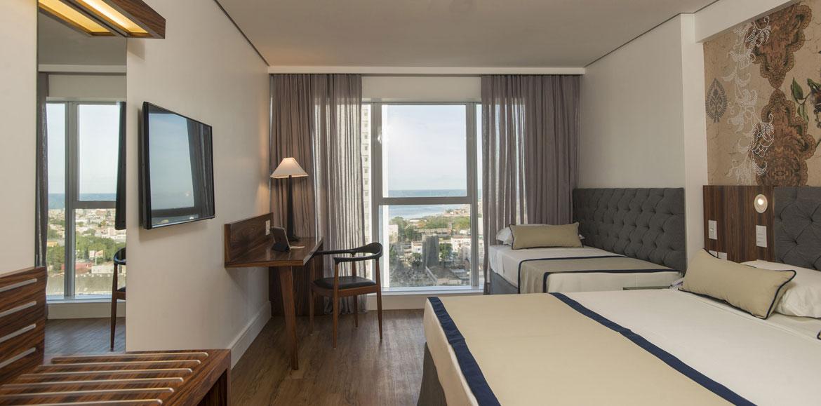 Hotel Luzeiros Recife Zewnętrze zdjęcie The photo shows a modern hotel room. It features two beds with a simple design, one larger and one smaller. There's a large window with sheer curtains, allowing natural light to fill the space and offering a view of the outside. A wooden desk and cha