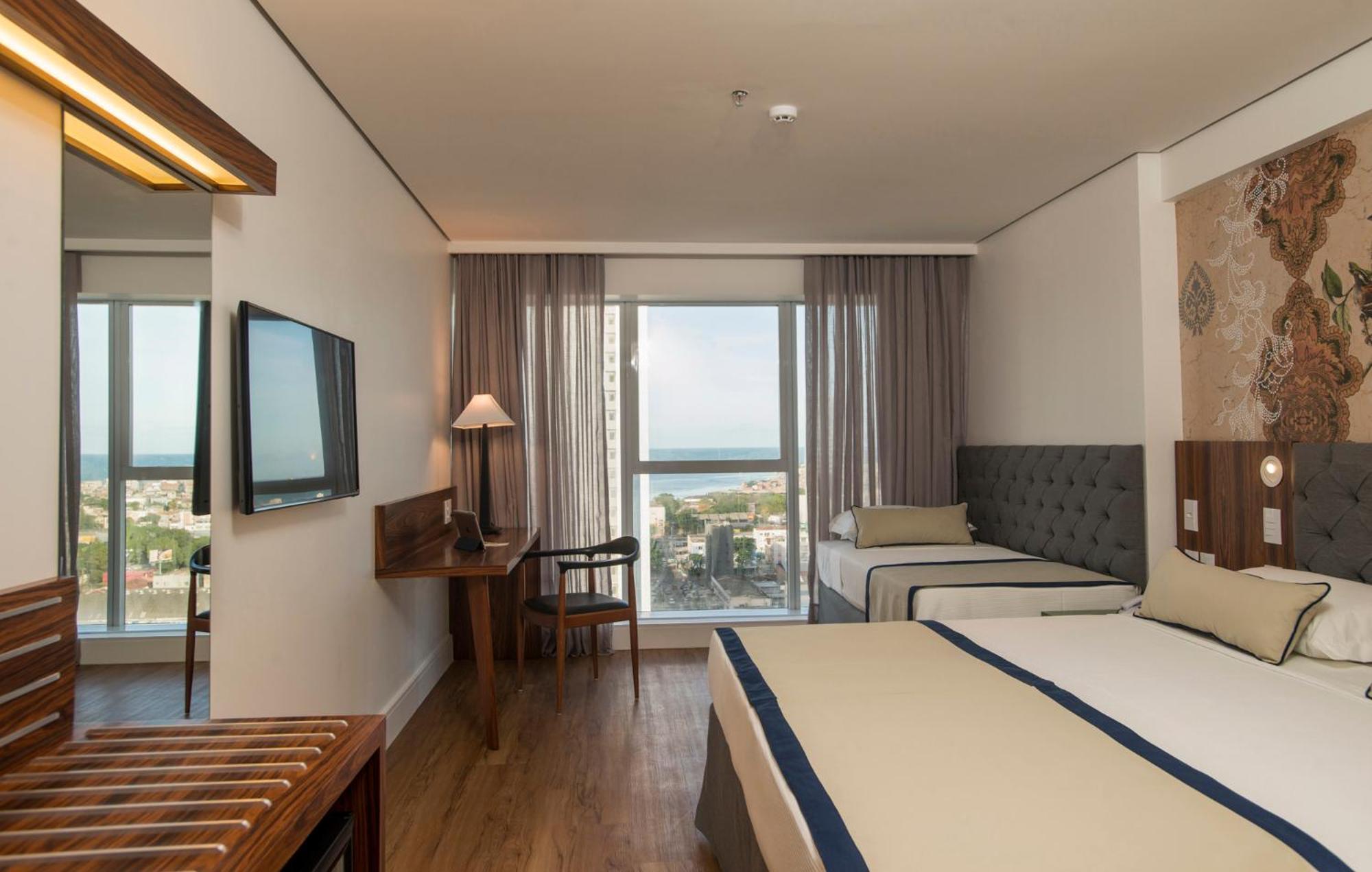 Hotel Luzeiros Recife Zewnętrze zdjęcie The photo shows a hotel room that features a modern and comfortable design. There are two beds: one larger bed and a smaller twin bed. The room has large windows with curtains that allow natural light to enter, offering a view of the outside, possibl